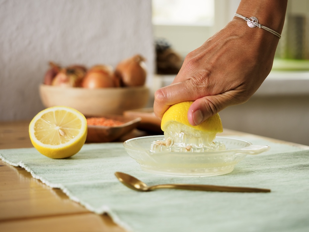 nutritionist mindful juicing a fresh lemon in her healthy kitchen